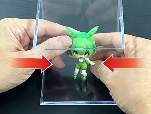 横に置いたケースへ、左右から手を入れてフィギュアを置く